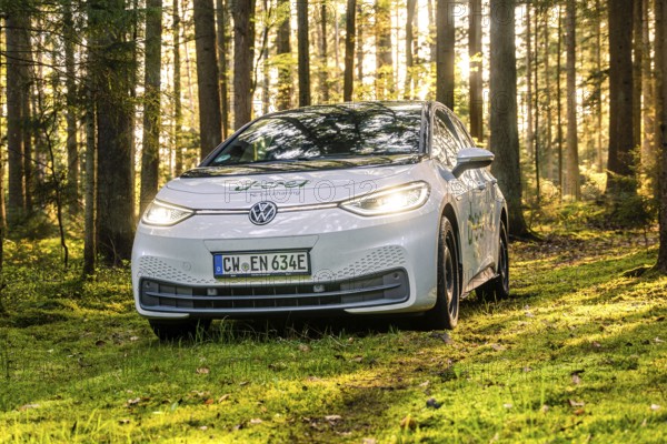 A white car in the forest with sunbeams, license plate CW EN 634E, Deer E-Carsharing, VW ID3, Calw,
