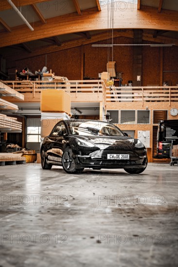 Black car parked in a wood-panelled workshop with modern architectural design, Deer e-car sharing,