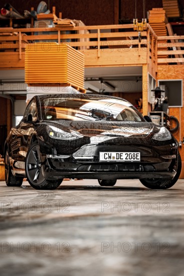 Black Tesla in a workshop environment with industrial flair, Deer e-Carsharing, Tesla Model 3,