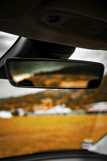 Rearview mirror in car with blurred view of landscape and buildings in background, Deer