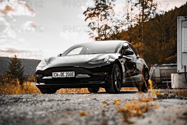 Black Tesla on a street at sunset in natural surroundings, Deer e-Carsharing, Tesla Model 3, Calw,
