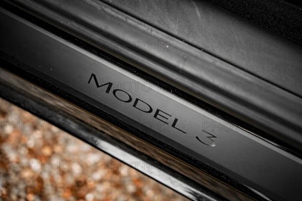Close-up of a black car with model 3 emblem on a metallic surface, Deer E- car sharing, Tesla Model