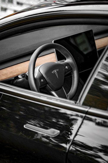 Black steering wheel with wood decor in modern car interior, side perspective, Deer e-car sharing,