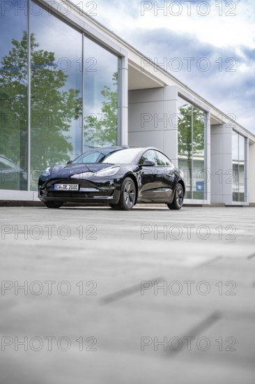 Black Tesla in front of a reflecting glass building on a cloudy day, Deer E-Carsharing, Tesla Model
