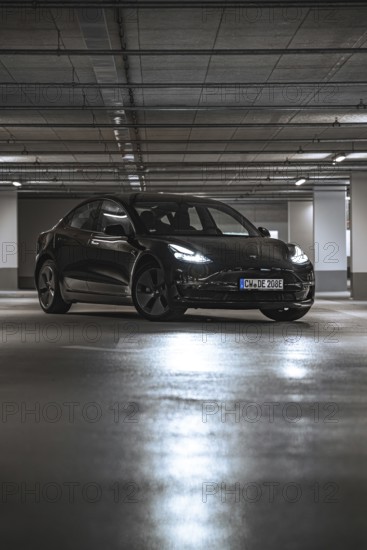 Black car in a parking garage with reflecting lights on the ground, Deer E-Carsharing, Tesla Model