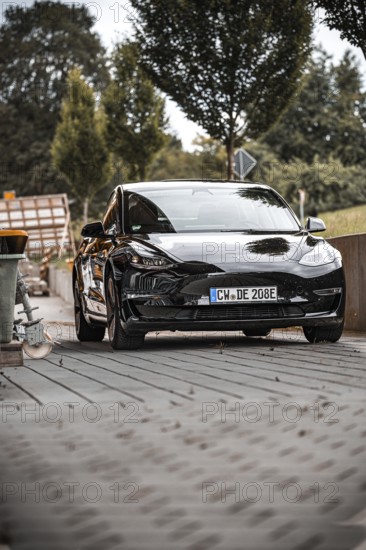 Black car from the front with surroundings and trees in the background, Deer e-Carsharing, Tesla