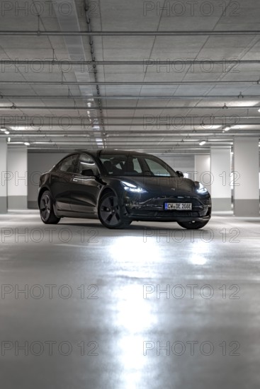 Black Tesla centrally positioned in empty, well-lit parking garage, Deer e-Carsharing, Tesla Model