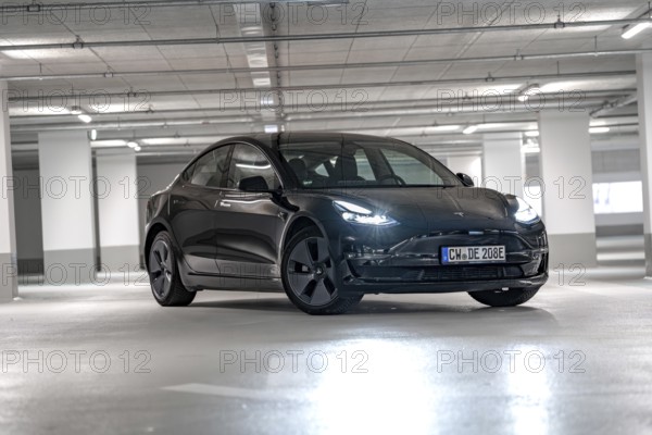 Black Tesla, headlights on, placed centrally in empty parking garage, Deer e-Carsharing, Tesla
