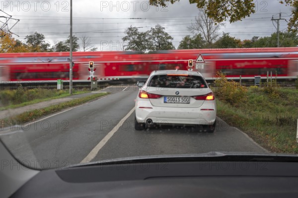 Regional train crosses a restricted level crossing, cars waiting in front of it, Fürth