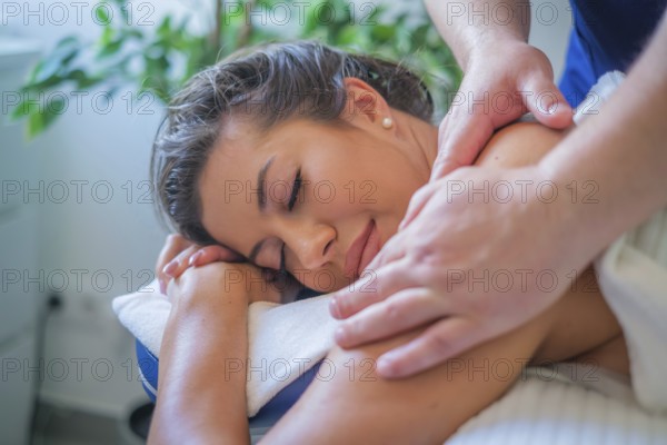 A woman enjoys a soothing back massage by a professional therapist using oil in a serene spa salon
