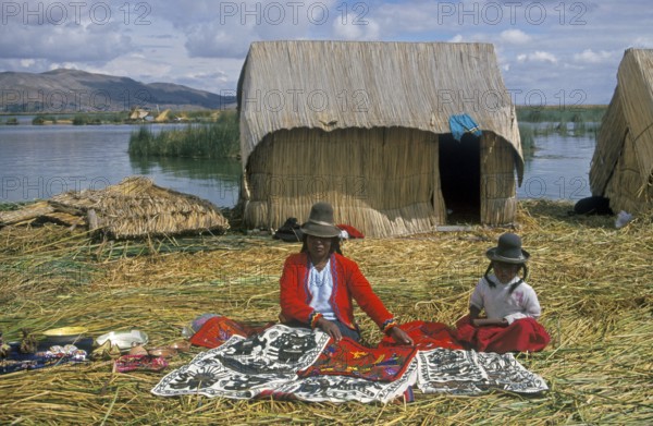 Mother and little daughter sell souvenirs on a floating Uro island in Lake Titcaca, Andean