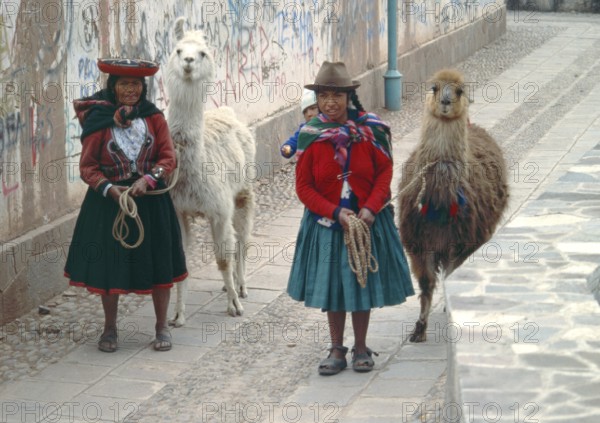 Traditionally dressed woman with llamas and small children in Cusco, Peru, Andean Highlands, South