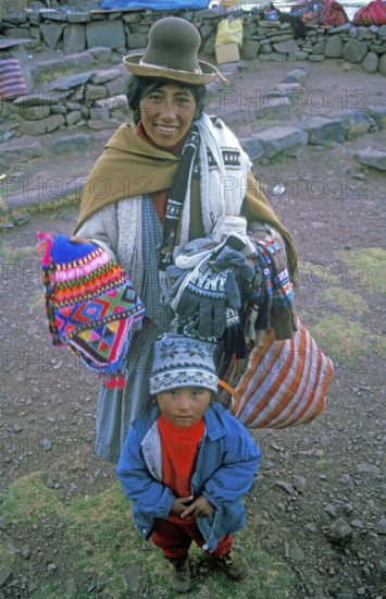 A woman with a small child sells souvenirs to tourists at the Sillustani ruins on Lake Umayo near