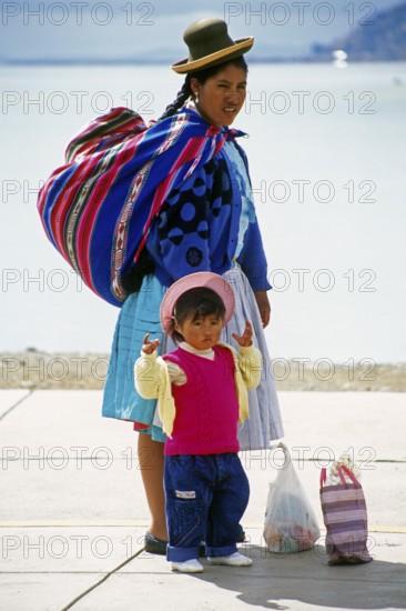 Traditionally dressed young woman with young daughter at Lake Titicaca in Puno, Andean Highlands,