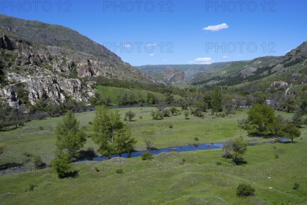 Extensive green valley with a small river and hill background. Peaceful natural landscape, Kura