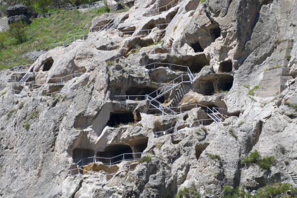 Nested monastery in rocks with caves and balustrades. Historical stone architecture, cave town,