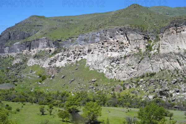 A rocky cliff with numerous caves carved into the rock face, cave town, cave monastery, Kura River,