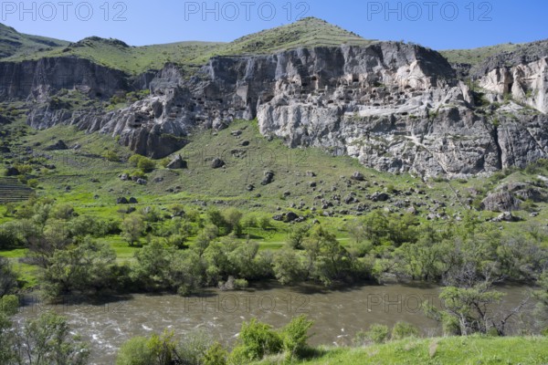 Rocky cliffs and flowing river in a green setting. Picturesque scenery, Kura river, cave monastery,