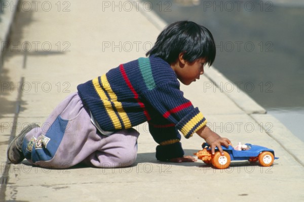 Little boy playing with toy car, Puno, Andean Highlands, Peru, South America, September 1997,