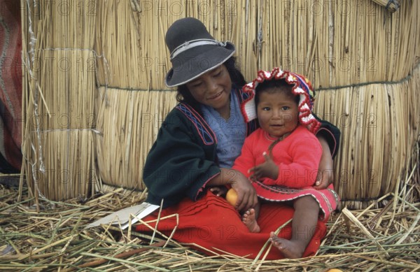 Children sitting in front of a reed hut on a floating Uro island in Lake Titcaca, Peru, South
