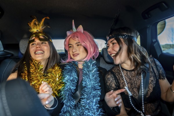 Young women friends celebrating new year's eve in costume, laughing and carefree in the back seat