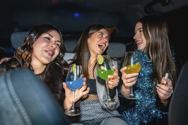 Three young women having fun traveling in a car at night, laughing and cheering with vibrant