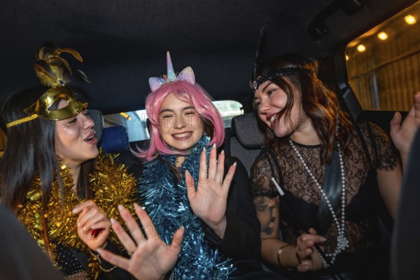 Three young women wearing festive costumes and garlands are happily laughing and dancing while