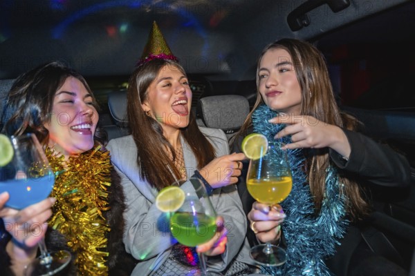 Three young women are happily celebrating a party in a car, enjoying colorful cocktails and good