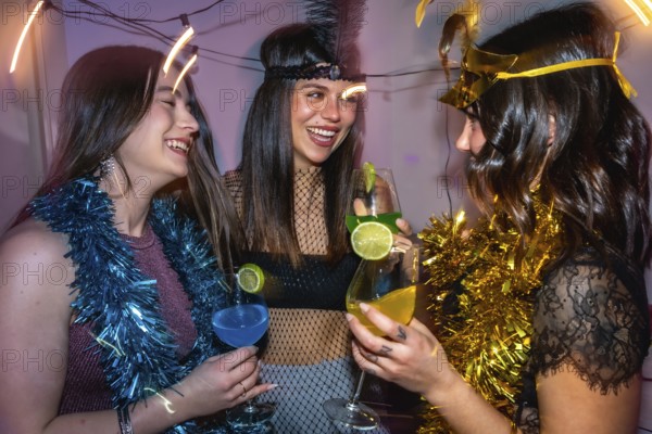Young women friends laughing and cheering with colorful cocktails, celebrating together during a