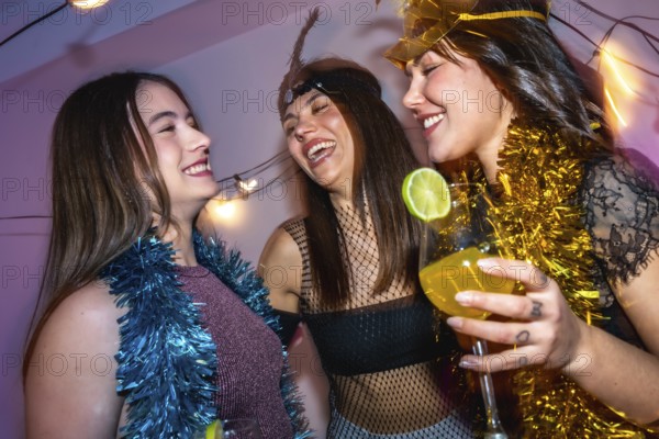 Three young women wearing party tinsel and costumes are happily celebrating new year's eve with