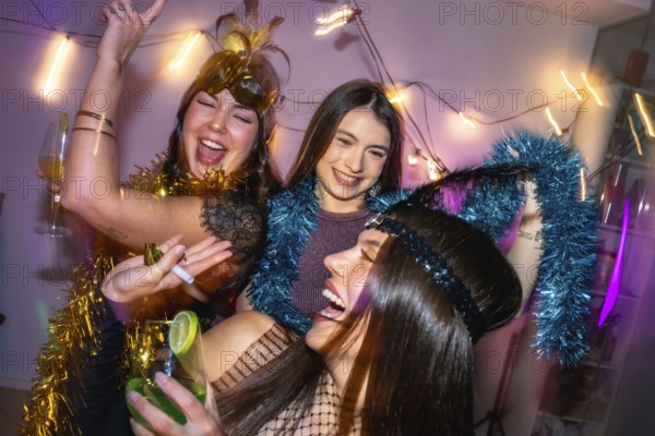 Three young women laughing and dancing, celebrating a festive new year's eve or costume party at