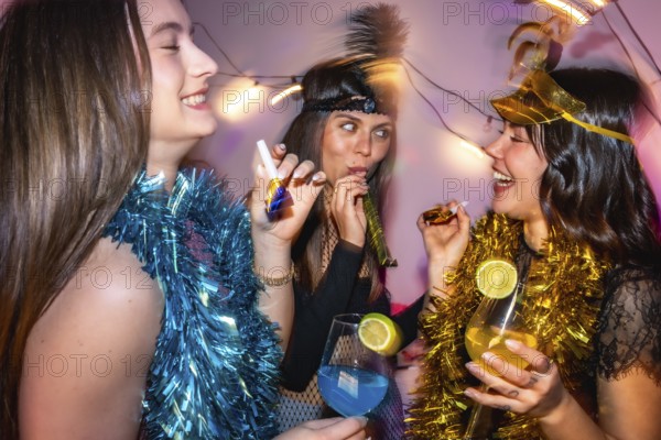Three happy young women enjoying a lively new year's eve or costume party, wearing festive
