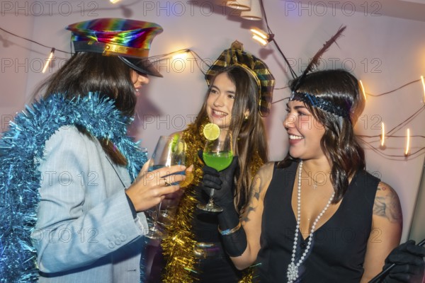 Three happy young women enjoying a festive new year's eve or costume party with drinks and tinsel
