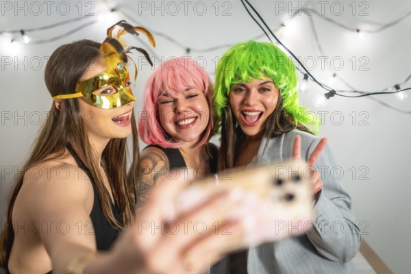 Girls friends celebrating a new year's eve or costume party, laughing and taking a selfie with a