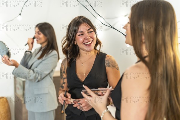 Young women friends applying makeup and styling hair, laughing and bonding as they get ready at