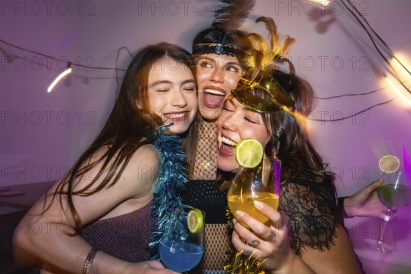 Three happy young women embracing, laughing and enjoying a festive celebration filled with