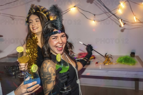 Young women in 1920s style costumes celebrating at home with cocktails, string lights and disco