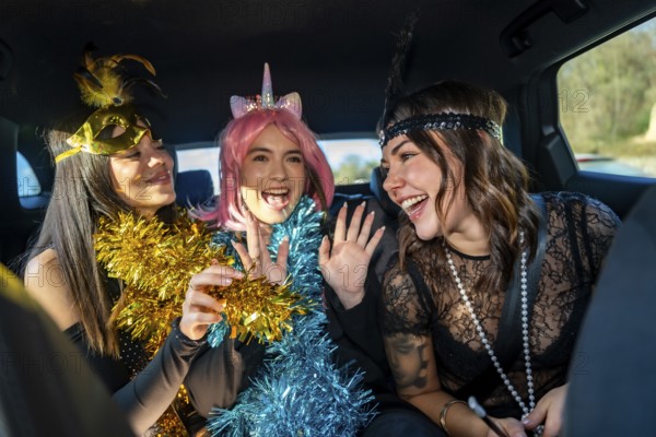 Happy young female friends wearing party costumes, tinsel garlands, and accessories, laughing and