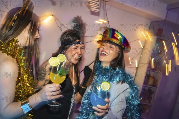 Young women friends enjoying a festive costume party at home, laughing and holding refreshing