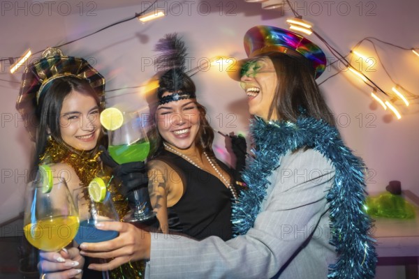 Three smiling young friends wearing party costumes and festive accessories celebrating a special