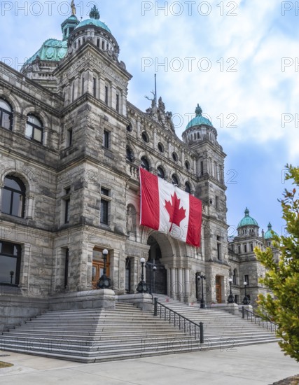 Parliament buildings in victoria, british columbia, proudly displaying a large canadian flag,