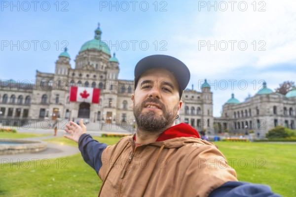 Happy bearded tourist taking a selfie with outstretched arm in front of the parliament buildings in