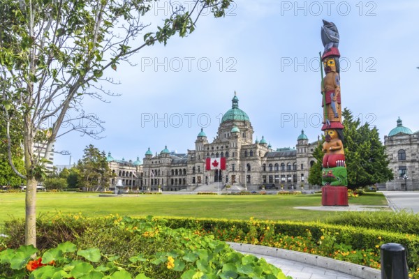 Canadian flag waving in the wind in front of the british columbia parliament buildings with a