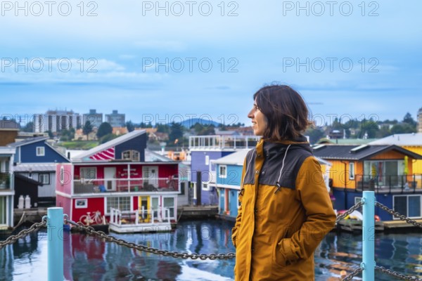 Young woman tourist admiring the colorful floating houses of fisherman's wharf park in victoria,