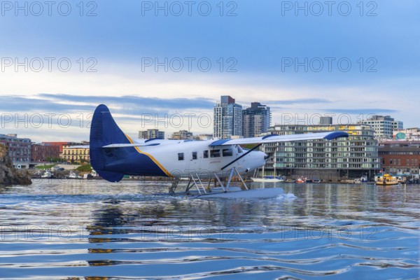 Seaplane is landing in the inner harbour of victoria, british columbia, with the city skyline in