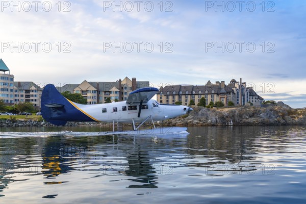 Seaplane taking off in the harbor of victoria, british columbia, with hotels and residential