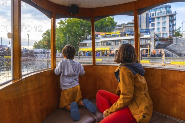 Mother and son are enjoying a harbor tour of victoria, british columbia, taking in the sights of