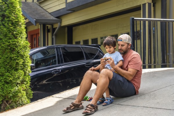 Father and son bonding while playing with a toy car on the driveway, sharing joyful moments