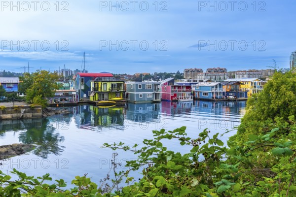 Colorful floating homes reflecting in the calm water at fisherman's wharf park in victoria, british