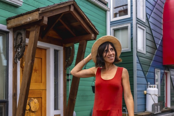 Smiling tourist holding her straw hat while visiting the colorful houses in the fisherman's wharf